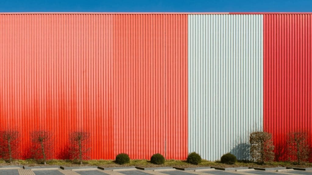 Commercial building exterior with bold red and sage green corrugated metal siding