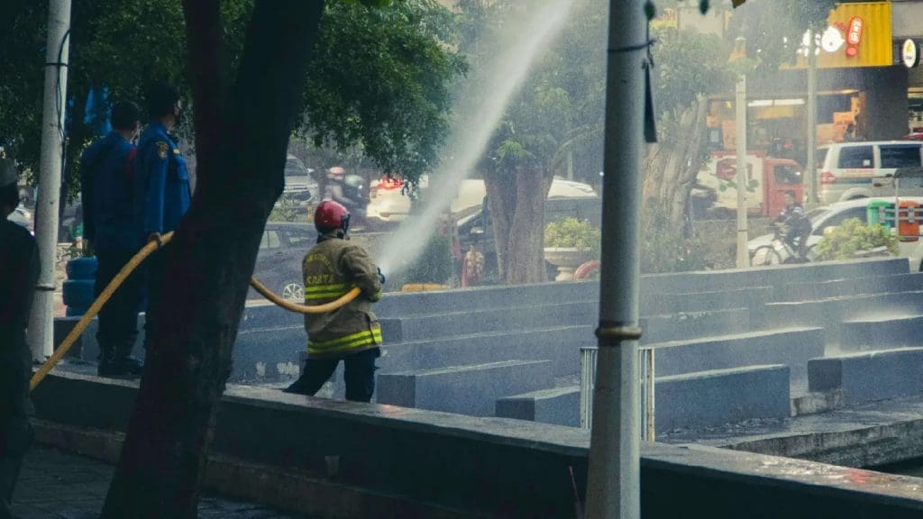 Firefighter hosing down a fire scene on a city street