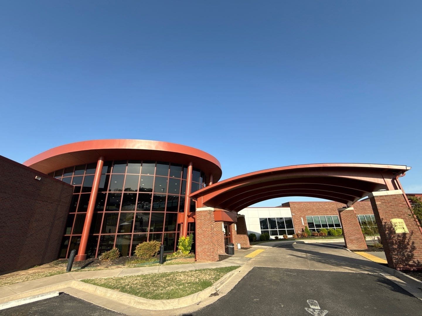 large commercial building exterior painting with curved architectural canopy and glass facade in Ardmore Oklahoma by Derheim Painting
