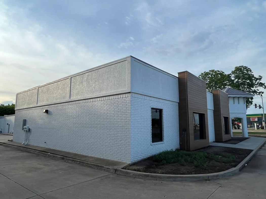 commercial brick building exterior repaint in white with brown accent panel by Derheim Painting Ardmore Oklahoma