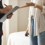 A contractor reviews a clipboard estimate with a homeowner during an interior painting walkthrough.
