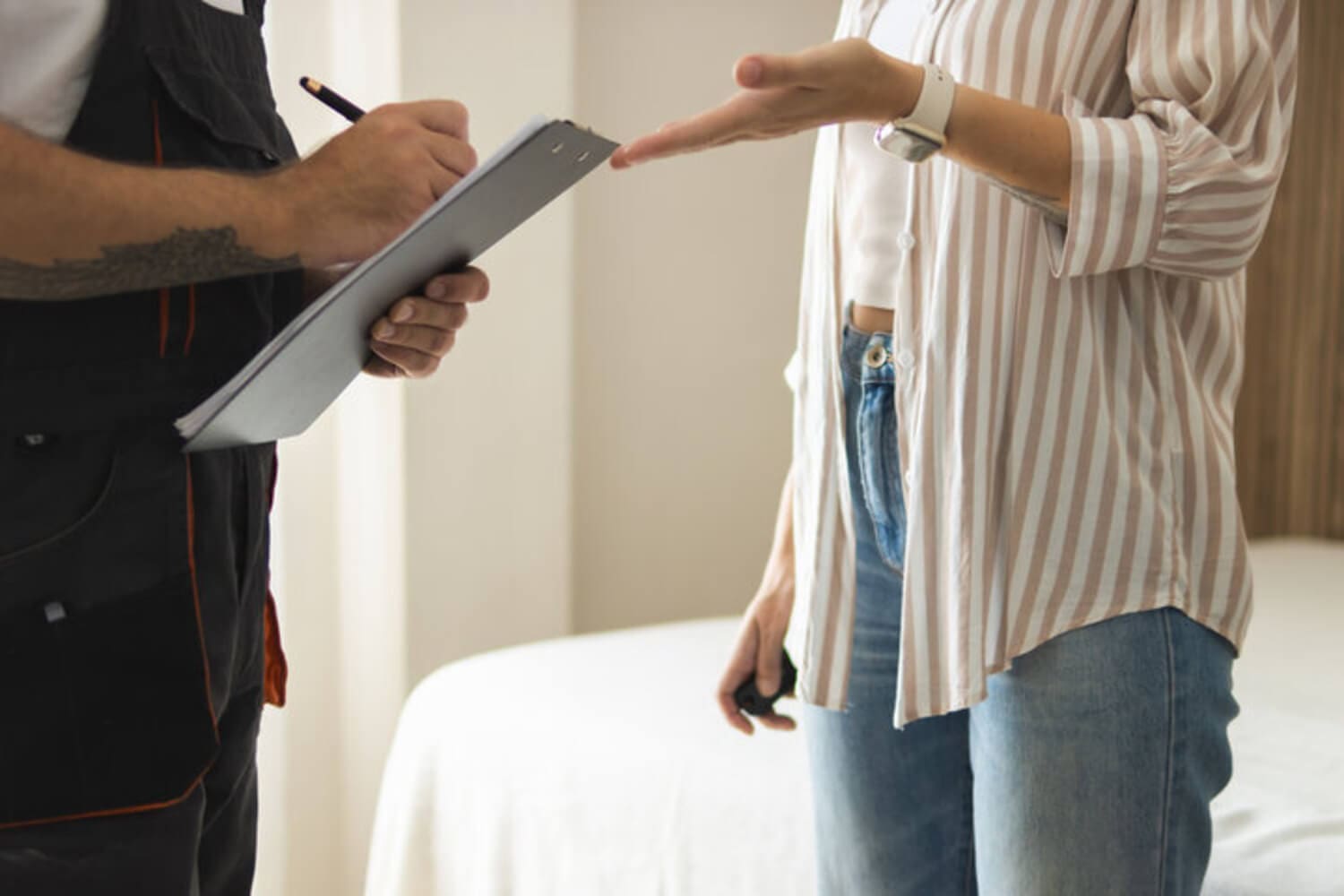 A contractor reviews a clipboard estimate with a homeowner during an interior painting walkthrough.