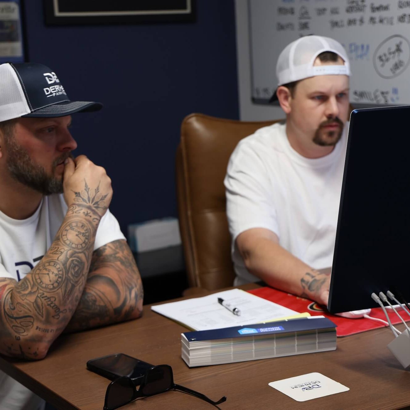 derheim painting owner and crew member working on estimate in front of computer in the painting company ardmore office