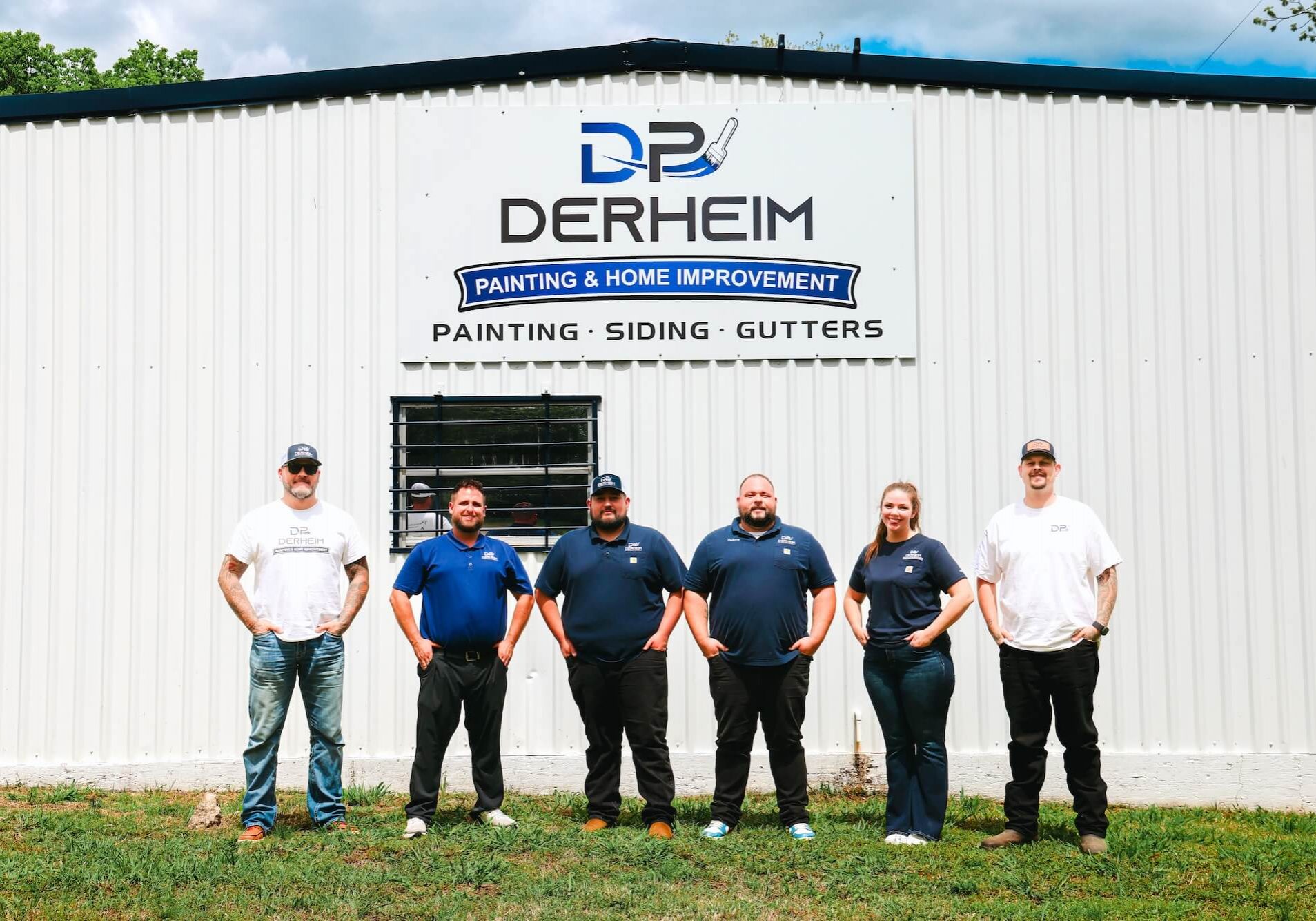 derheim painting and home improvement team in front of shop with their logo on a sign in front of the building